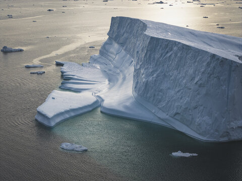 Aerial view of a massive iceberg floating in the dark waters of the Ilulissat Icefjord, showcasing intricate ice textures in Ilulissat, Avannaata Kommunia, Greenland.