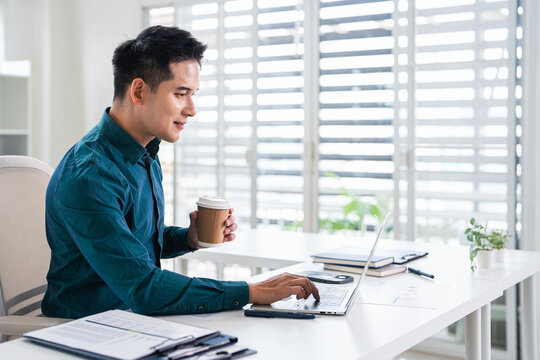 Businessman using laptop computer in office. Happy middle aged man, entrepreneur, small business owner working online.