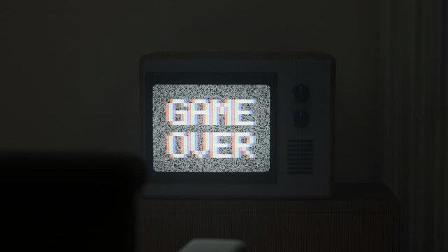 A 3D render of a retro television set in a dark room displaying a pixelated game over message on a static screen with white noise