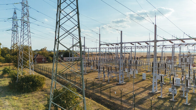 Aerial view of an electrical power substation with high-voltage transmission towers and metal infrastructure surrounded by a fenced rural landscape in Sremska Mitrovica, Vojvodina, Serbia.