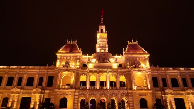 Wide shot of the illuminated French colonial Saigon City Hall building with golden night lighting in Ho Chi Minh City, Vietnam