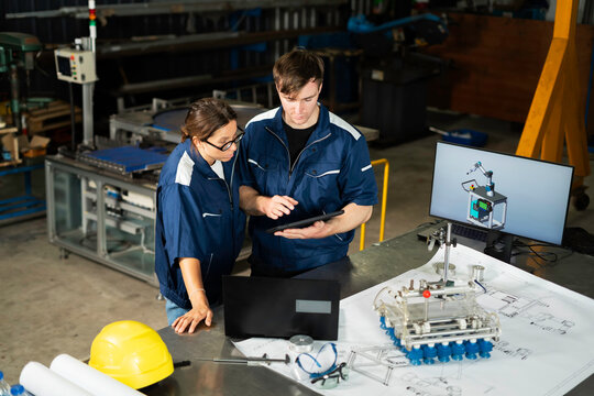 Industrial Engineers Inspecting Machine Component in Manufacturing Factory