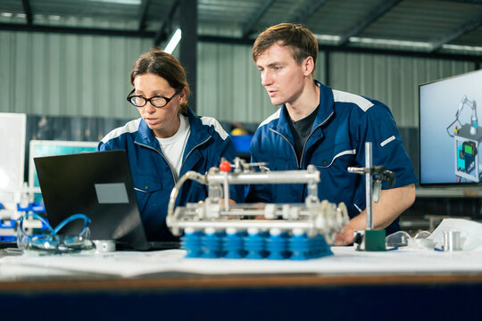 Industrial Engineers Inspecting Machine Component in Manufacturing Factory