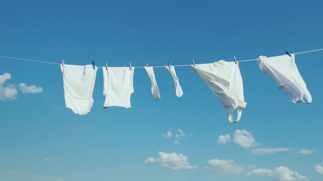 White laundry hanging on clothesline against blue sky background outdoors.