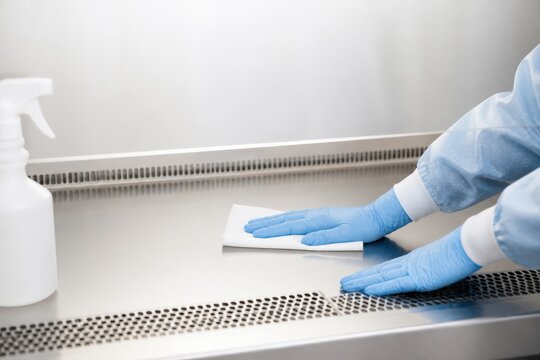 Sterile compounding pharmacy hands cleaning an empty hood surface