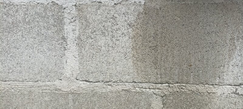 Concrete cinder block masonry wall background with subtle moisture discoloration and raw cement finish, perfect for architectural overlays and rustic urban graphics