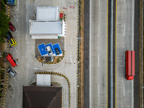 Aerial view of a highway rest area with a red truck driving on the road and parked cars at a electric vehicle charging station in Salatiga, Central Java, Indonesia.