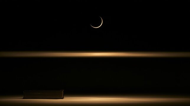 Crescent moon shining above a closed book in the dark night with a horizontal glowing light beam
