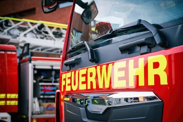 Nahaufnahme eines roten Feuerwehrfahrzeugs mit großem Schriftzug „Feuerwehr“ und Drehleiter im Hintergrund. © mpix-foto