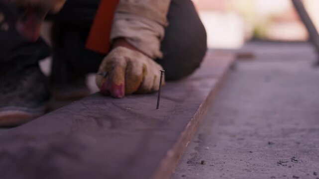 Worker driving nail into timber formwork with hammer