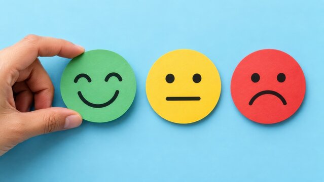 Hand holding green happy face icon on World Smile Day against a blue background with neutral and sad icons