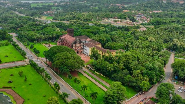 Aerial view of the Church of St. Francis of Assisi surrounded by lush green trees, manicured lawns, and roads in Old Goa, Goa, India.