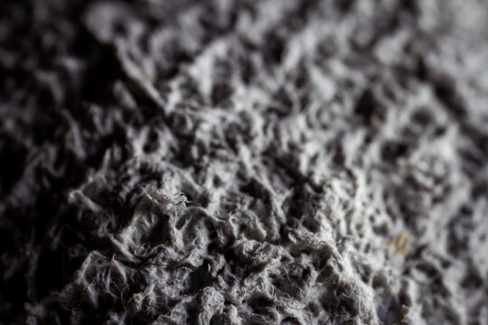 Extreme close up of old gray handmade paper clay with a structure and rough texture. Paper recycling. Selective soft focus, shallow depth of field.