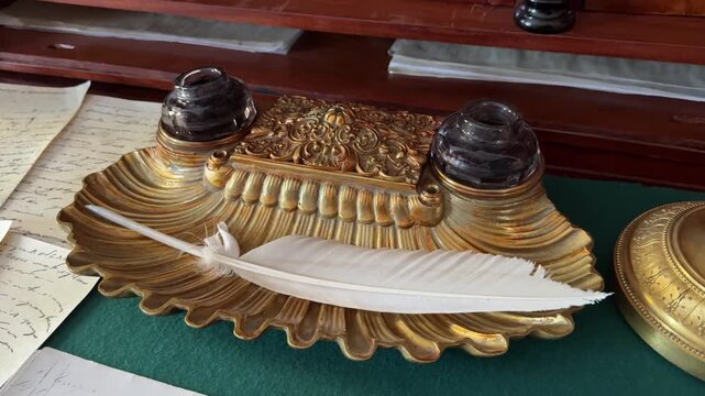 A vintage bronze stand with a white goose feather and ink.