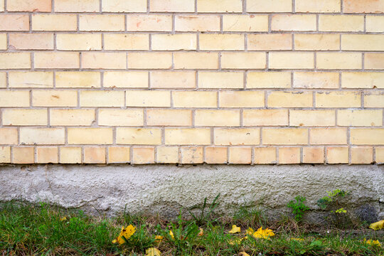 Yellow brick wall background with green grass. Architectural detail.