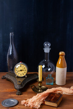 Various old vintage objects on brown wooden table by the black wall. Still life.