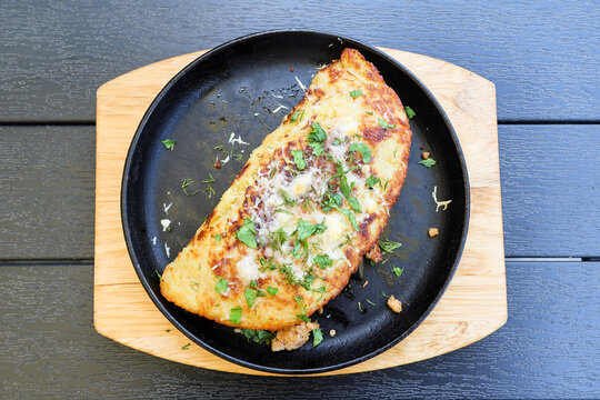 Huge traditional Belarusian potato pancake draniki filling the entire cast iron frying pan, rustic homemade food, close up golden crispy texture.