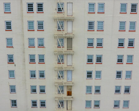 Aerial view of a building facade featuring a central metal fire escape and symmetrical windows in Los Angeles, California, United States.