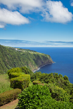 Ponta do Sossego viewpoint offers a panoramic view of the rugged coastal landscape of S&atilde;o Miguel island, featuring steep green cliffs descending to the Atlantic Ocean under a clear blue sky