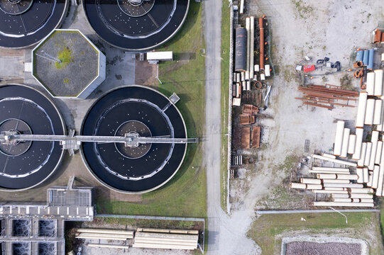 Aerial view of the Waste Water Treatment plant with circular sedimentation tanks, industrial pipes, and maintenance equipment in Richmond, British Columbia, Canada.