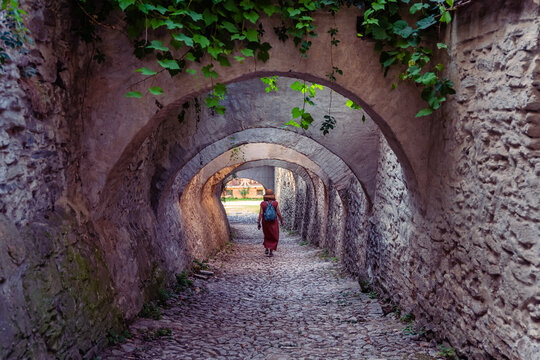 Woman walking through arched stone passage at Biertan fortified church in Transylvania Romania