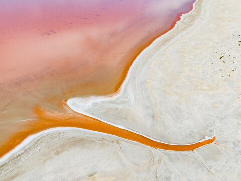 Aerial view of a vibrant pink salt lake with striking orange mineral deposits and white salt crusts in the Mallee region, Woorinen North, Victoria, Australia.