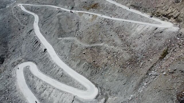 Aerial View of Serpentine Road in Himalayan Mountains with Snow-Capped Peaks and Rocky Terrain, Clear Sky, Daytime Scene