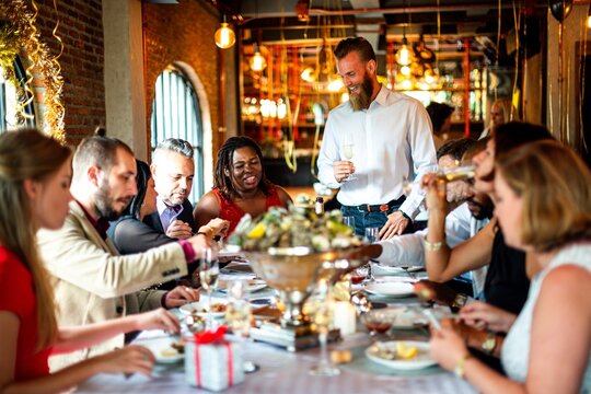 Diverse group enjoying a festive meal in a warmly lit restaurant setting.