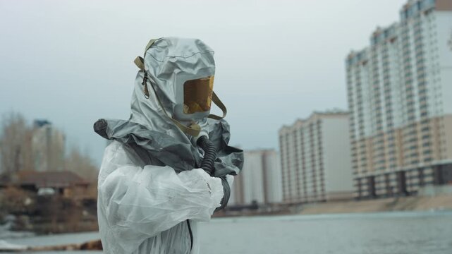 Hazmat suit at frozen shore scientist surveying radiation with dosimeter urban highrises in background, overcast sky, frost on concrete, cautious posture, sampling and documentation, tense atmosphere