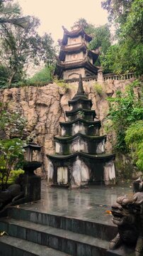 Low angle view of Xa Loi Pagoda tower surrounded by stone cliffs and lush greenery at Marble Mountains in Da Nang, Vietnam
