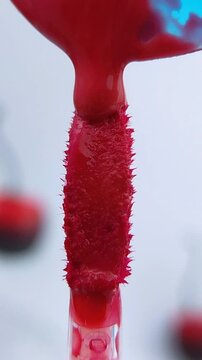 Red liquid melting or dripping on a mini brush. Beauty product advertisement concept. Vibrant color cosmetic tool for makeup application.