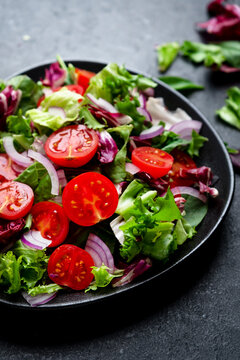 Gourmet vegetarian diet tomato salad, fresh vegetable blend on plate. Environmental sustainability represented by raw agricultural produce. Red onion slices adding flavor to healthy lifestyle menu.