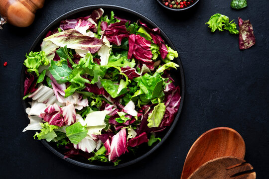 Fresh vegetable food healthy green salad near wooden cooking utensils. Organic vegan plant based nutrition concept for raw diet lifestyle. Delicious vegetarian cooking dish for autumn crop harvest.