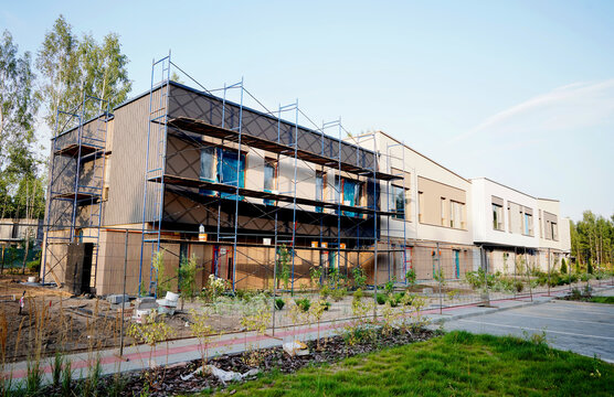 Townhouse construction. Scaffolding for painting building's facade. Facade construction work on modern townhouse building.Construction of modern two-story duplex. 