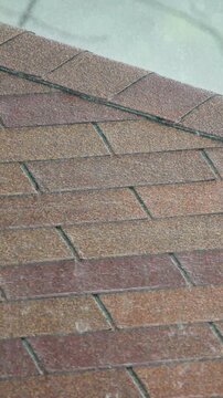 Close up footage of brown asphalt shingles on pitched roof during daytime.
