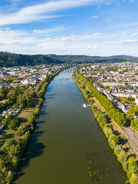 Aerial view of the Moselle river flowing through the historic city of Trier, featuring the ancient Roman bridge and lush riverbanks in Trier, Rhineland-Palatinate, Germany.