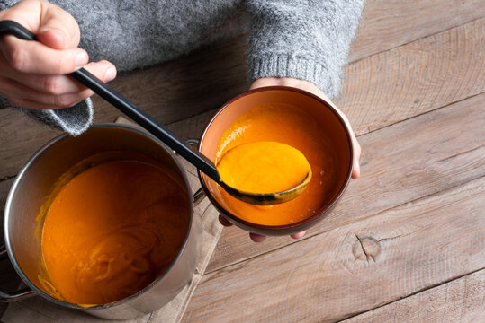 Person's hands ladling soup into bowl