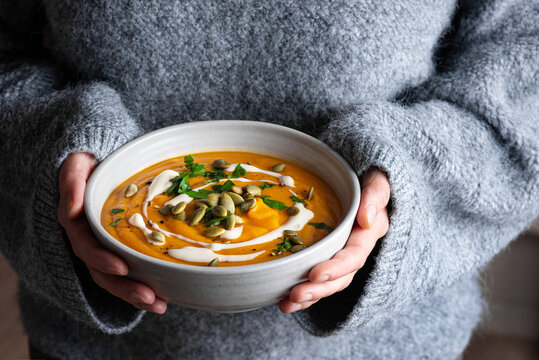 Bowl of pumpkin soup in woman hands