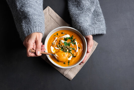 Woman in knitted sweater eating fresh pumpkin soup