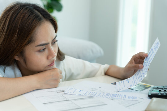 Stressed and headache asian woman with large bills or invoices no money to pay to expenses and credit card debt. shortage, Financial problems, mortgage, loan, bankruptcy, bankrupt, poor, empty wallet