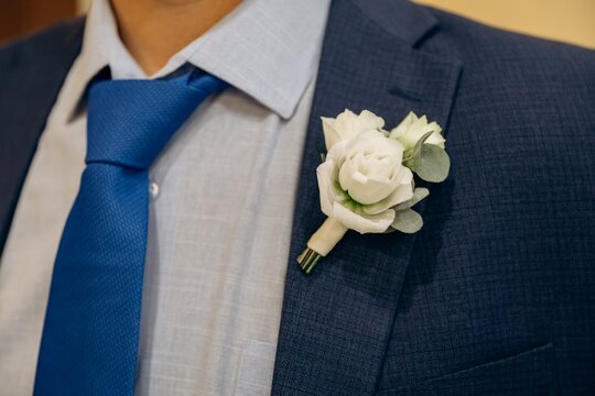 Elegant groom in a dark blue suit paired with a matching blue tie and a beautiful white rose boutonniere.