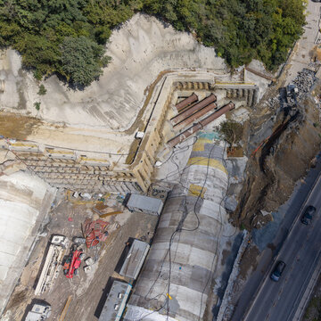 Aerial view of a tunnel construction site featuring concrete tunnel segments, steel support pipes, and heavy machinery near a hillside in Istanbul, Istanbul, Turkiye.