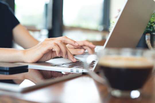 Close up of business woman using laptop surfing the net, remote working at coffee shop, online business concept.