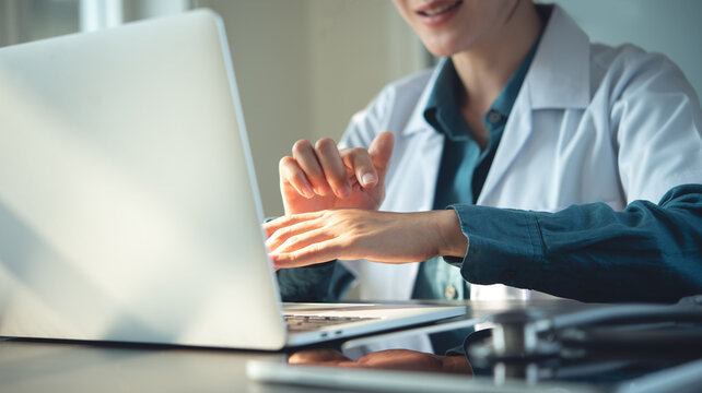 Asian female doctor talking to online patient on laptop screen sitting at clinic office desk giving online consultation for domestic health treatment. Telemedicine remote medical
