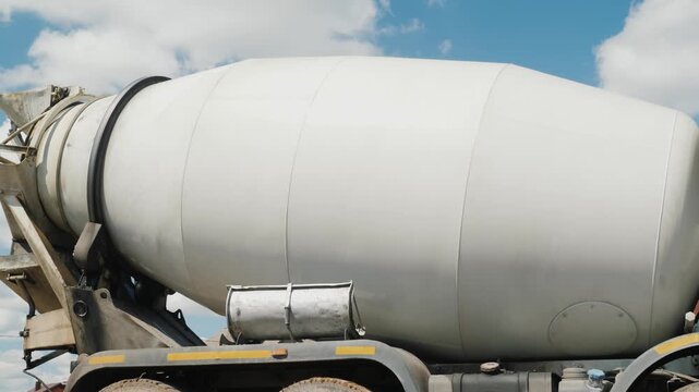Industrial cement mixer truck drum rotation closeup ready for concrete delivery at construction site under blue sky.