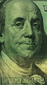 Benjamin Franklin dollar bill close up. Benjamin Franklin on dollar bill appears in real camera recording. Close up view holds on printed currency as changing light reveals paper texture.