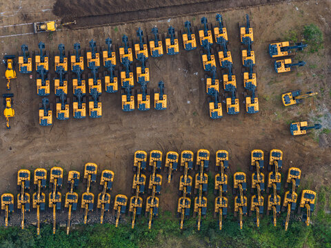 Aerial view of rows of yellow excavators parked in an organized construction equipment yard in Chakan, Maharashtra, India.
