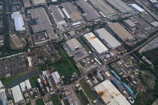 Aerial view of the industrial zone in Chakan featuring large factory buildings, warehouses with solar panels on rooftops, and connecting roads in Chakan, Maharashtra, India.