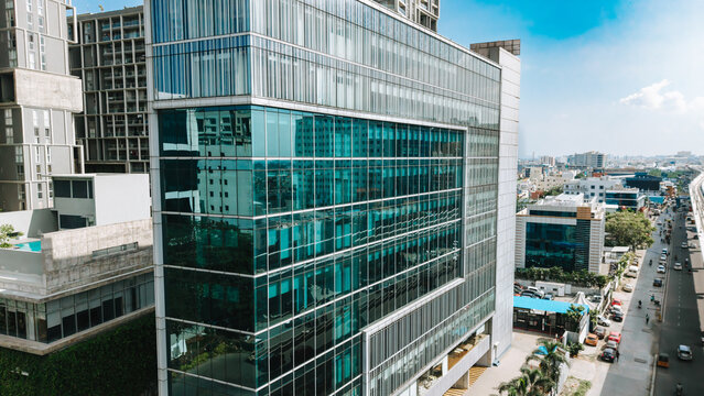 Aerial view of a modern glass-facade office building with reflective windows in an urban setting in India.