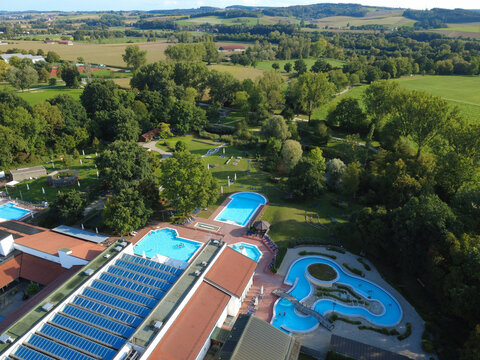 Aerial view of Thermal Spa Bad Birnbach featuring multiple outdoor swimming pools, lush green gardens, and solar panels on the building roof in the countryside of Bad Birnbach, Bavaria, Germany.